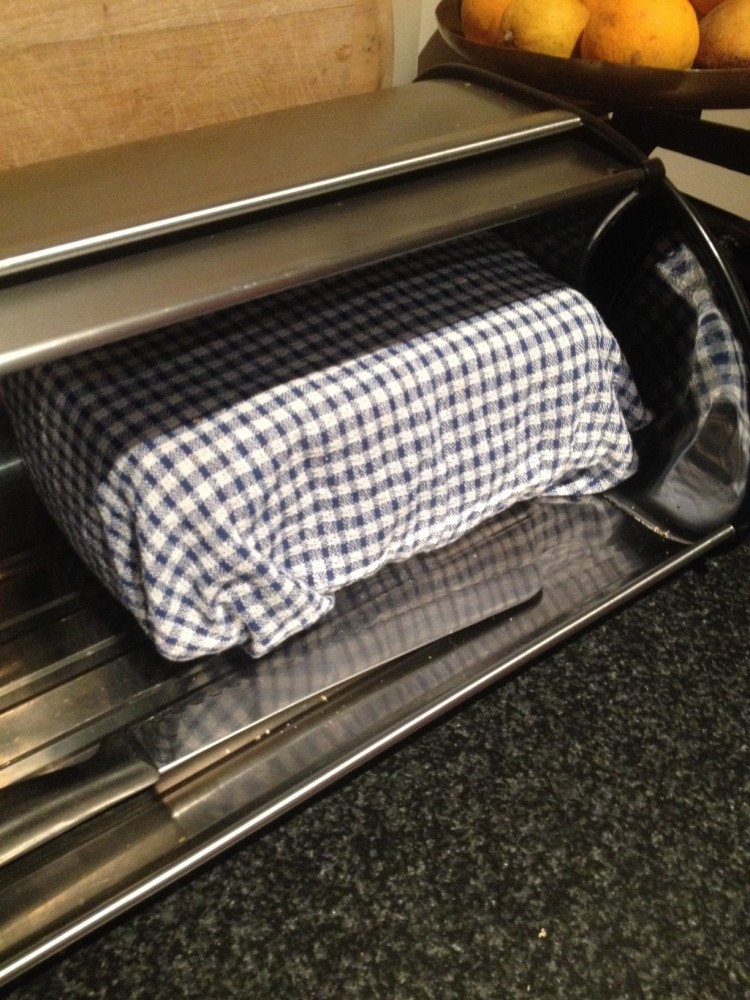 Homemade bread wrapped in a teatowel and stored in the bread tin.
