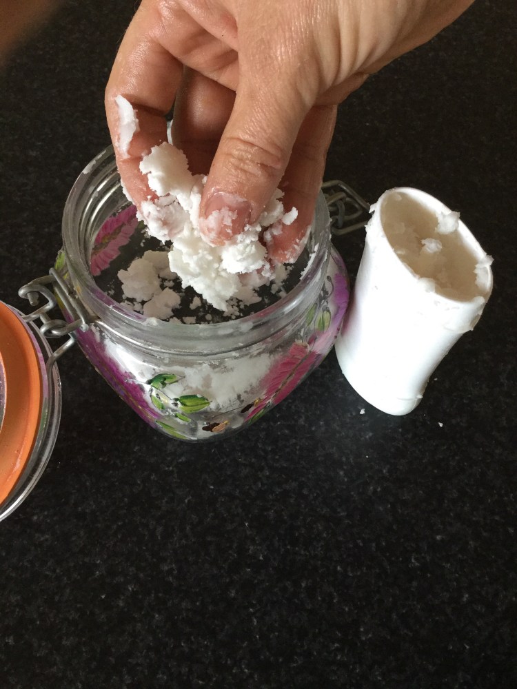 Stuffing my homemade deodorant mixture into my empty stick deodorant canister.