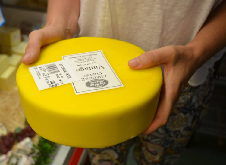 Tammy holding a 2kg wheel of cheddar cheese coated in wax.
