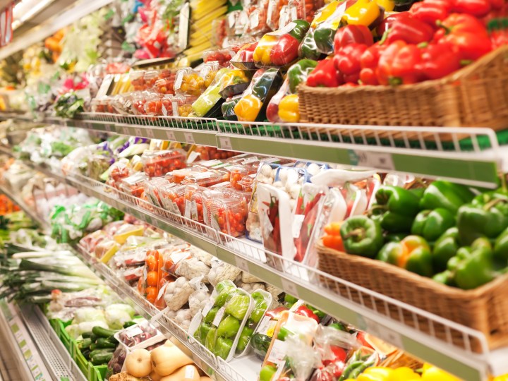Plastic packaged fruits and vegetables on supermarket shelves.